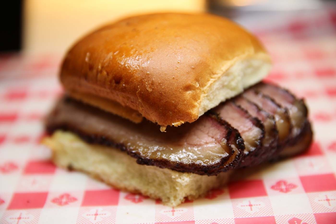Roast beef sandwich on a checkered deli paper wrapper, close-up view