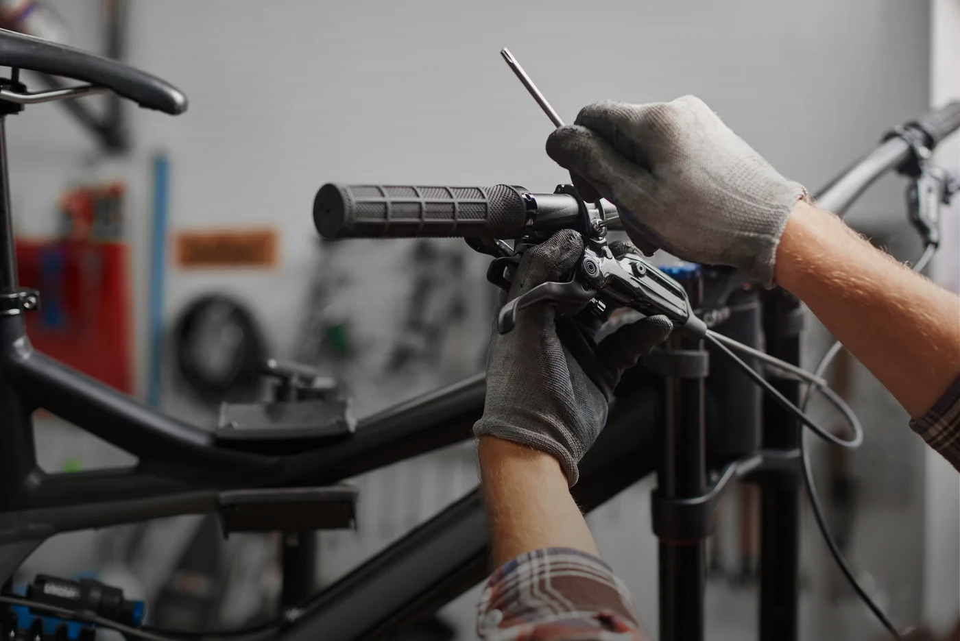 Person wearing gloves using a screwdriver to adjust bicycle handlebars.