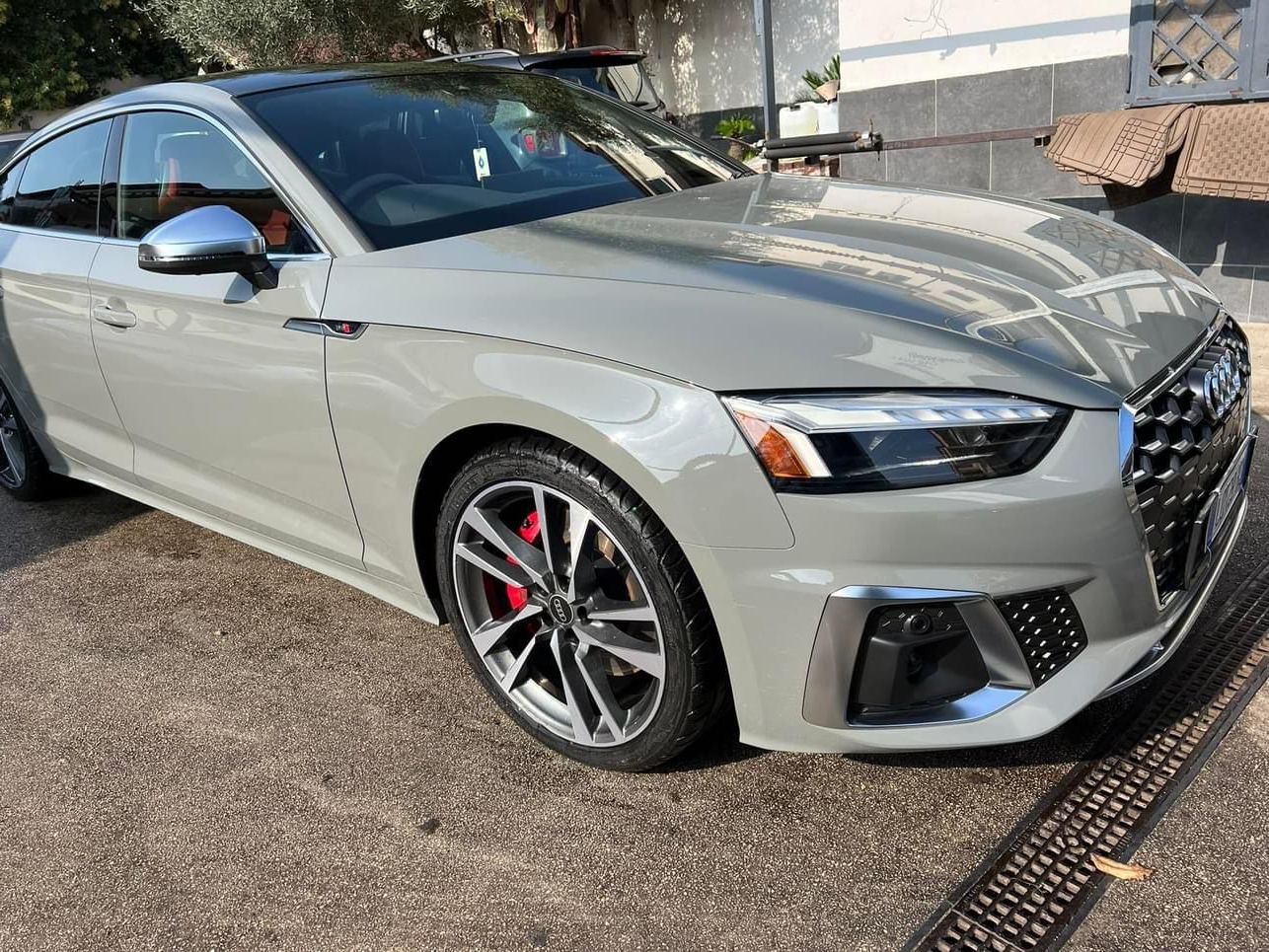 Audi S5 coupé grigia con pinze dei freni rosse parcheggiata sull'asfalto.
