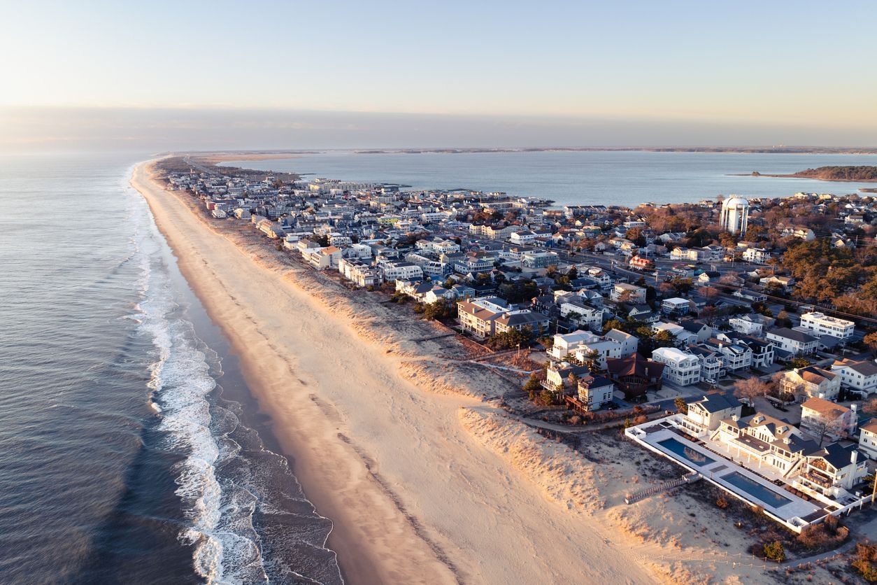 Aerial view of a beachside town along a long sandy shoreline at sunset.