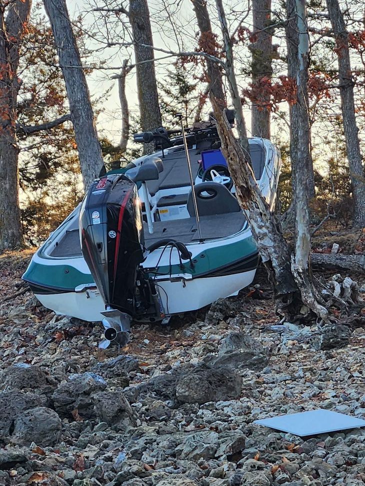 Small helicopter crashed in a snowy wooded area, wedged between trees.