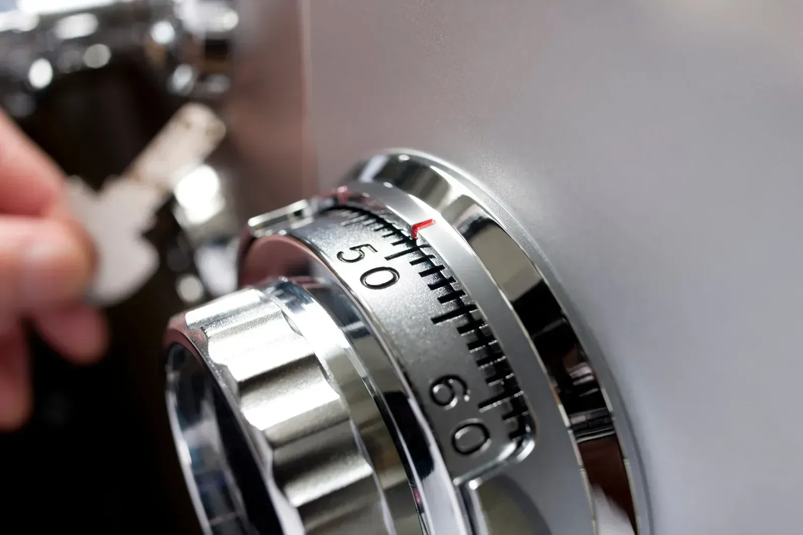 Close-up of a chrome safe dial being turned by a hand