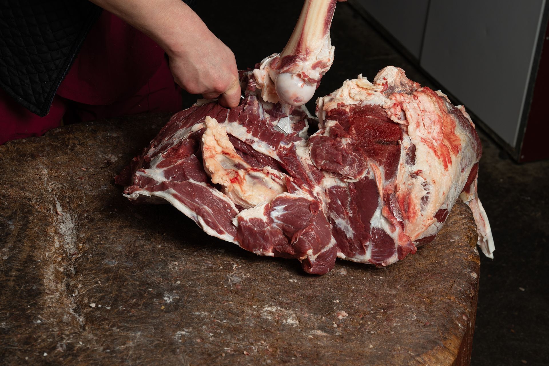 A person is cutting a piece of meat on a cutting board.