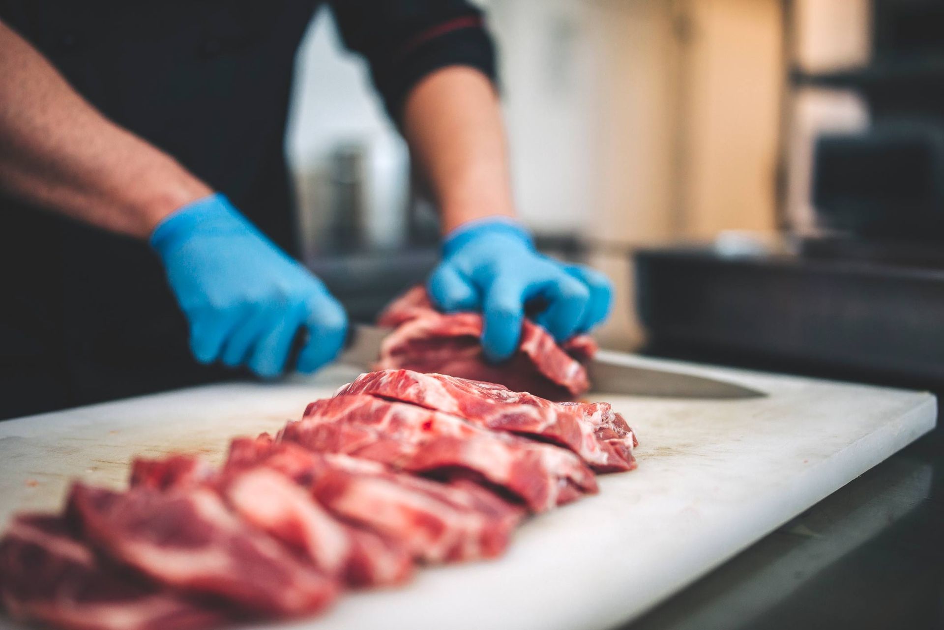 A butcher is cutting a piece of meat with a saw.