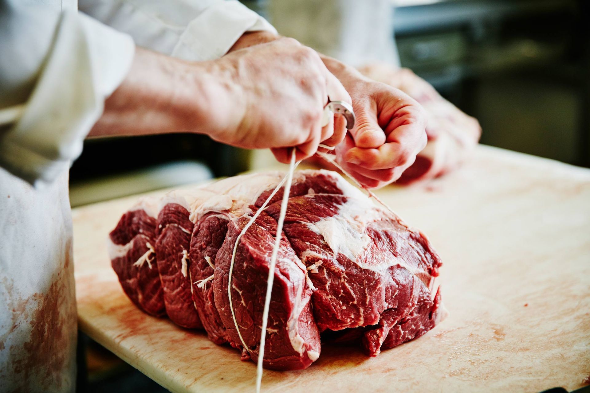 A piece of raw meat is sitting on a cutting board in a butcher shop.