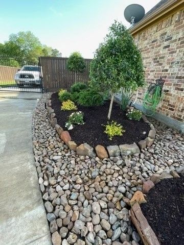 A garden with rocks and plants in front of a brick building.