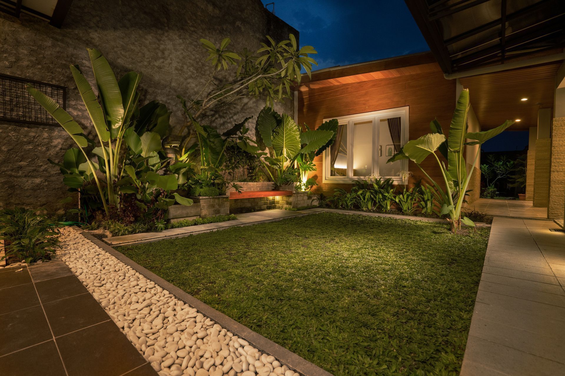 A house with a large lawn in front of it at night.