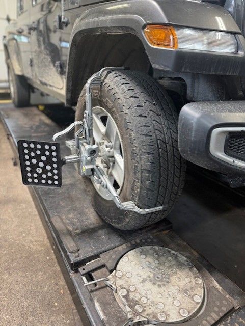 Jeep tire on alignment machine, gray vehicle, black and silver equipment, shop setting. | Dave's Automotive LLC