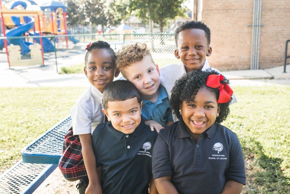 Five ISL students smiling, sitting outside on a picnic table