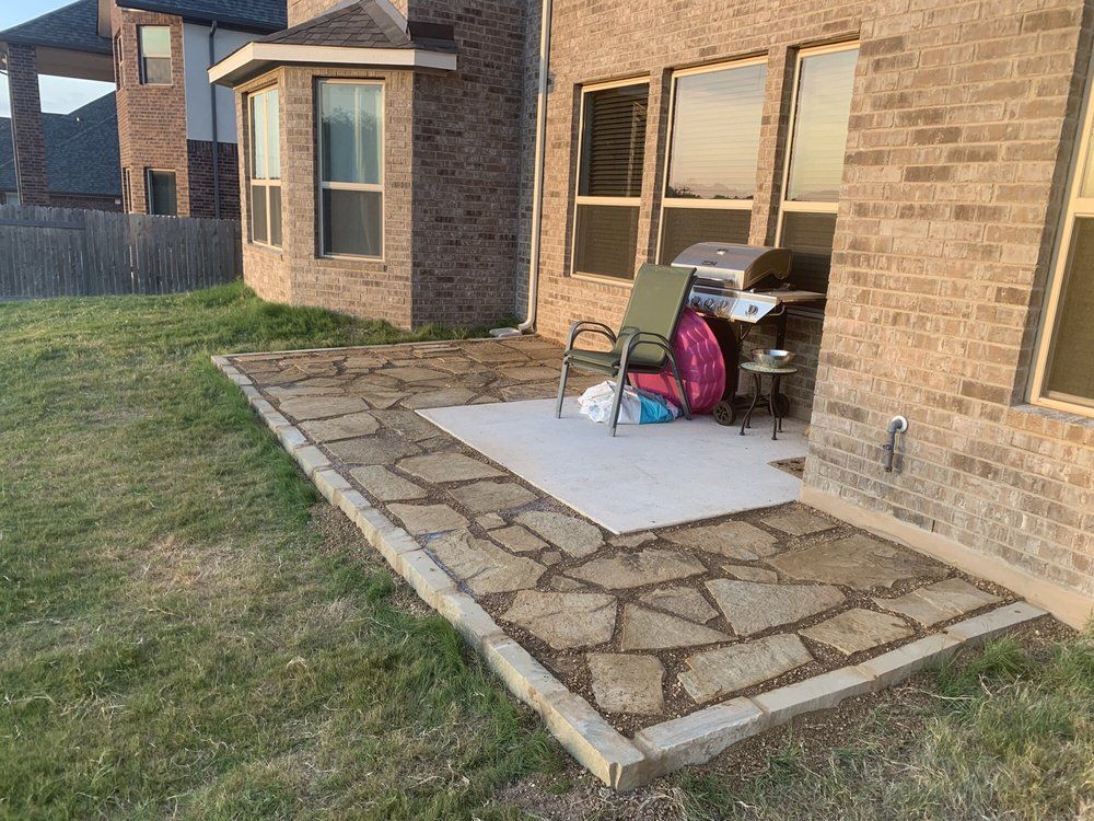 Flagstone patio with brick house, grill, and yard.