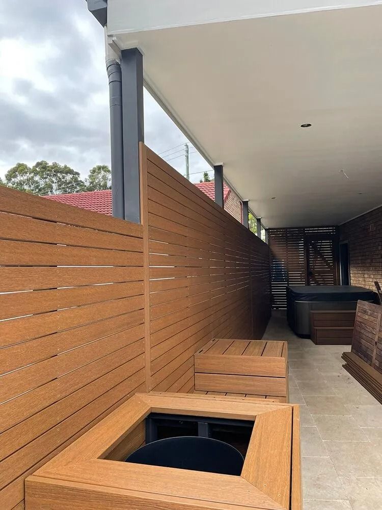 Outdoor patio with wooden privacy wall, built-in bench seating, and a square fire pit opening