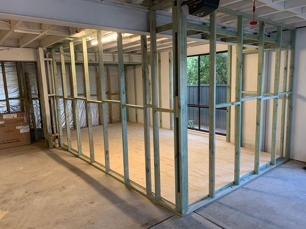 Framed interior walls under construction in a partially finished room with exposed wood studs and concrete floor
