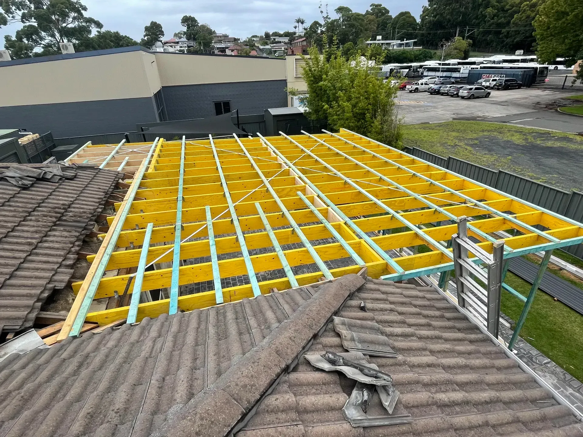 Roof under construction with yellow framing and workers’ materials on a building rooftop