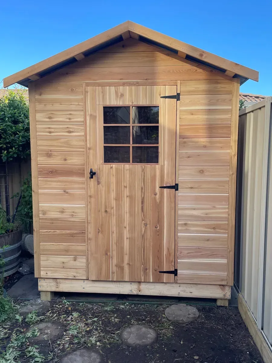 Wooden garden shed with double doors and a small window under a pitched roof.