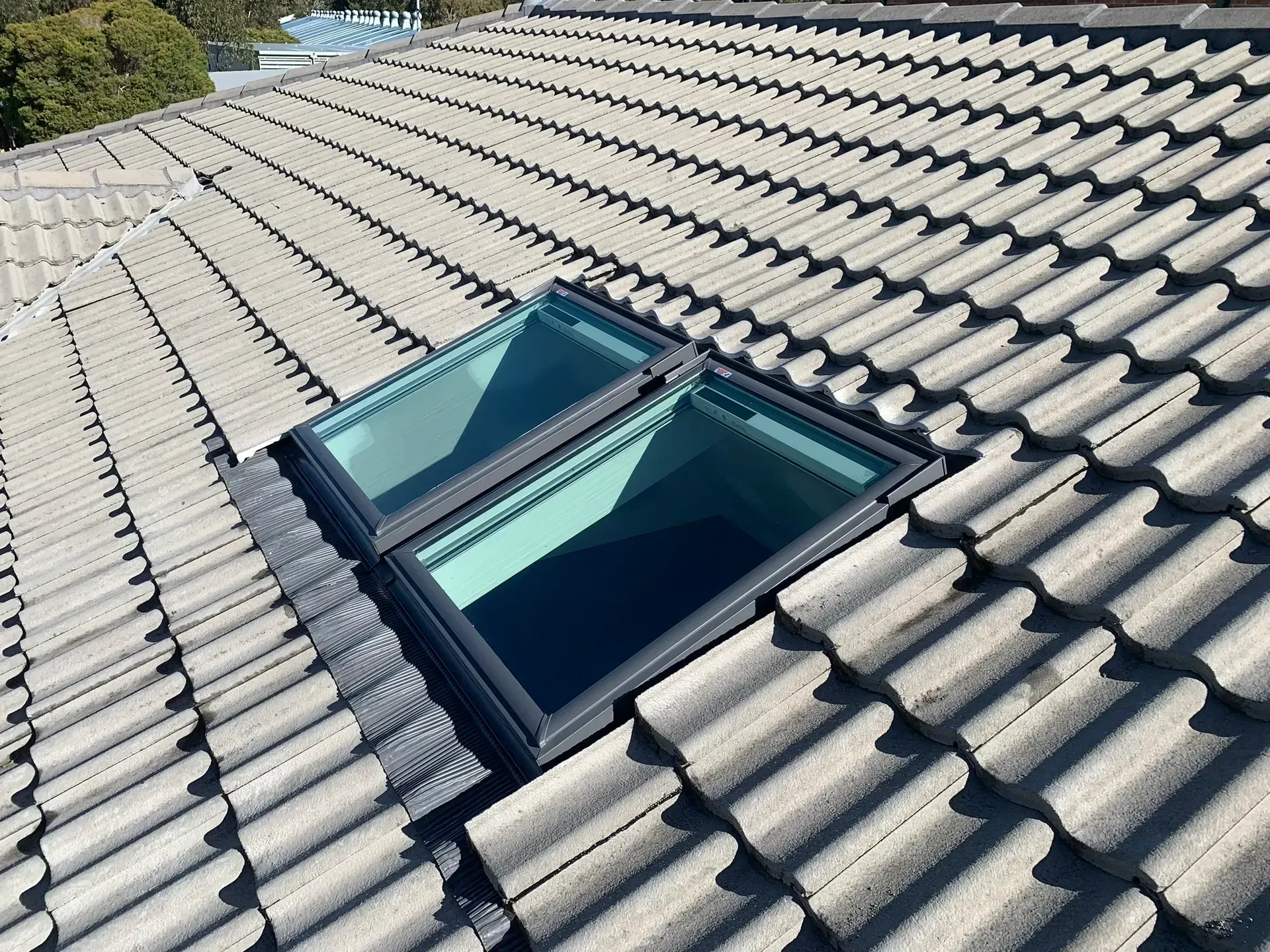 Skylight windows set into a gray tiled roof under clear daylight