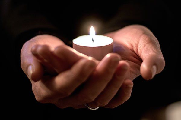 Eine Person hält eine brennende Kerze in ihren Händen