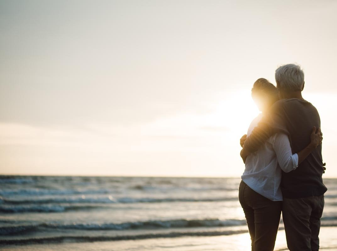 Ein Mann und eine Frau umarmen sich bei Sonnenuntergang am Strand.
