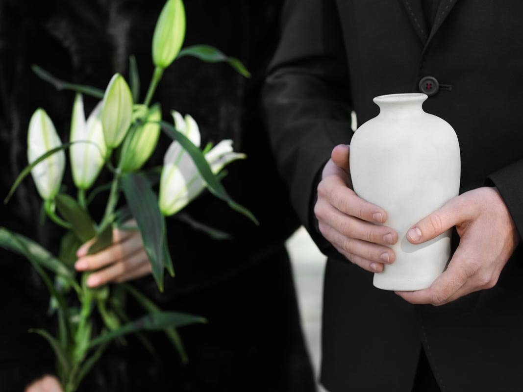Ein Mann hält eine weiße Vase und eine Frau hält Blumen.