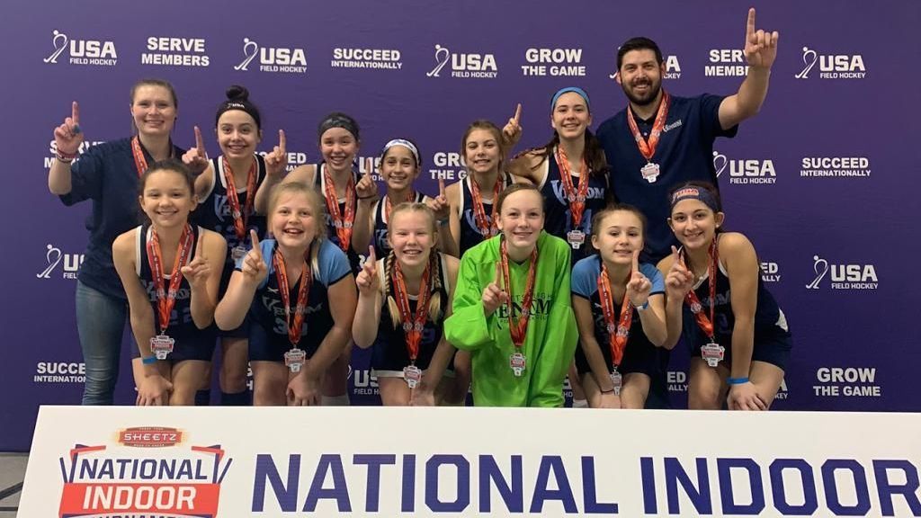 A group of people are posing for a picture in front of a sign that says national indoor tournament.