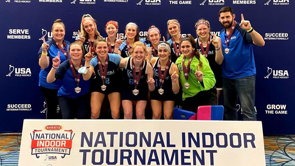 A group of people are posing for a picture in front of a national indoor tournament sign.