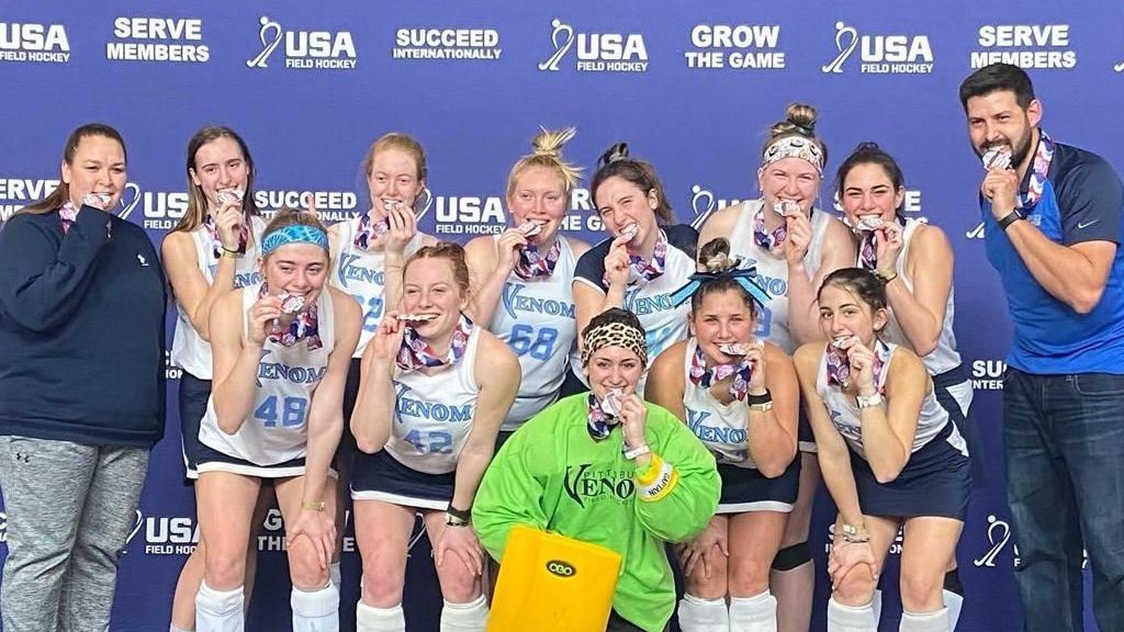 A group of female field hockey players are posing for a picture.
