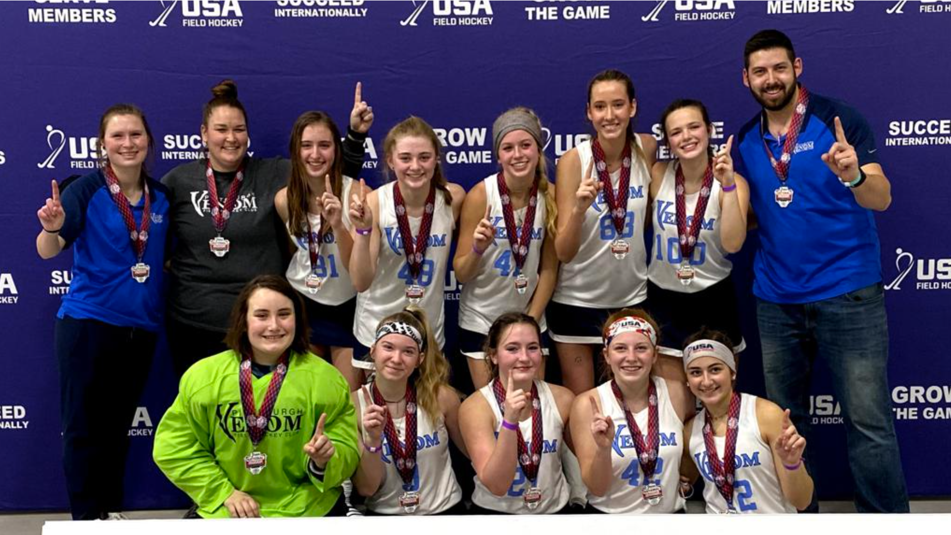 A group of people are posing for a picture in front of a national indoor tournament sign.
