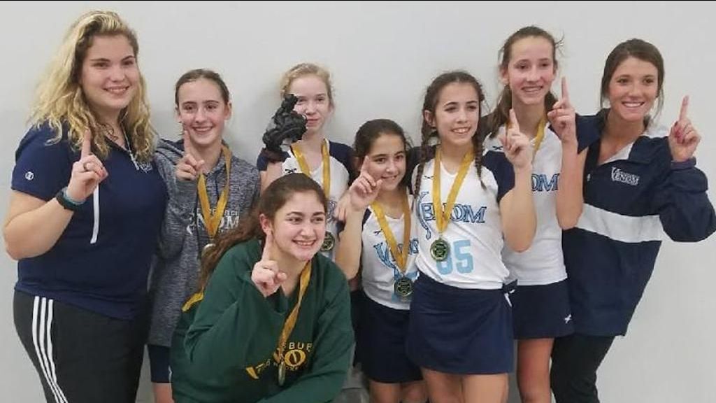A group of girls are posing for a picture and one has the number 15 on her shirt