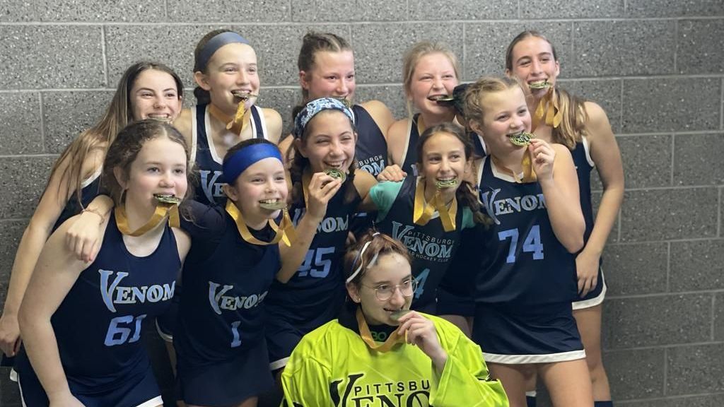 A group of young girls are posing for a picture with one wearing a jersey that says venom