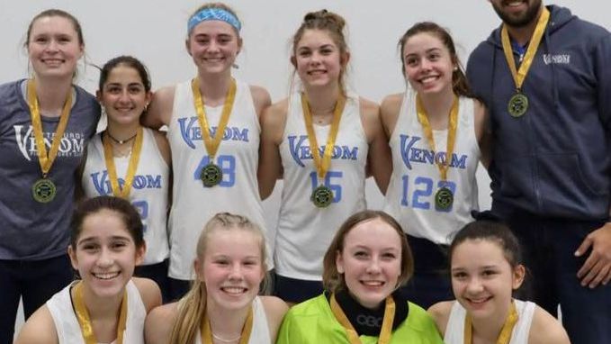 A group of young girls wearing venom jerseys pose for a picture