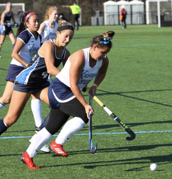 A field hockey player wearing a jersey that says ' kensington ' on it