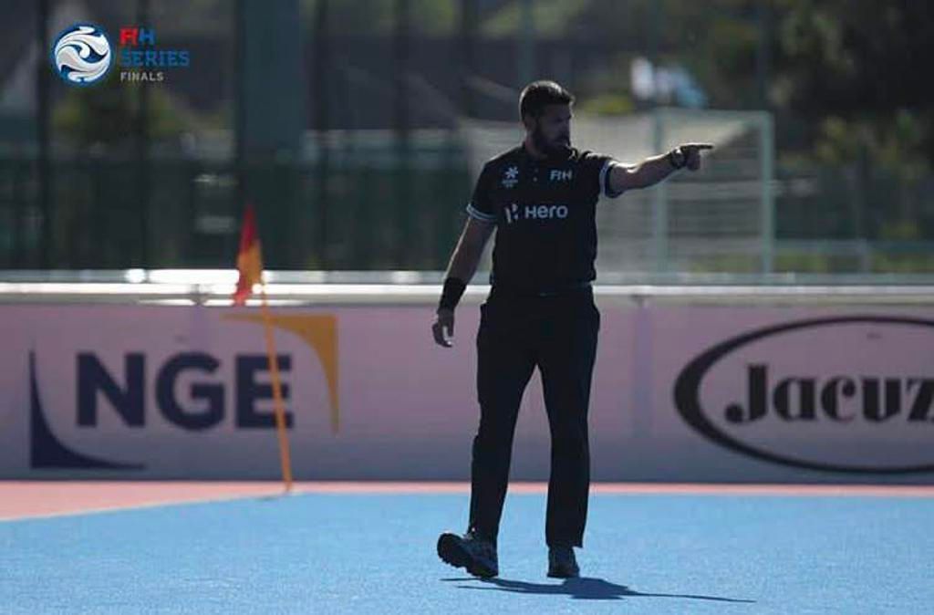 Hockey player in black uniform points to the right on a blue field.