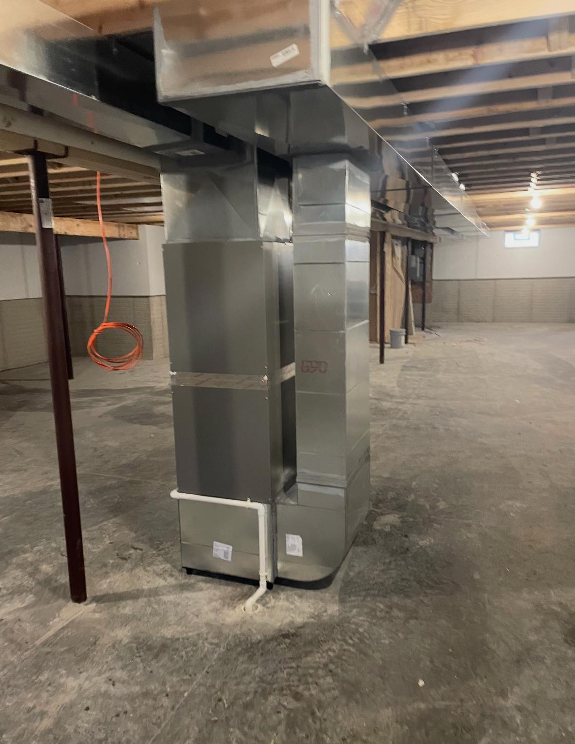 Basement utility room with metal HVAC ductwork and support columns on a concrete floor
