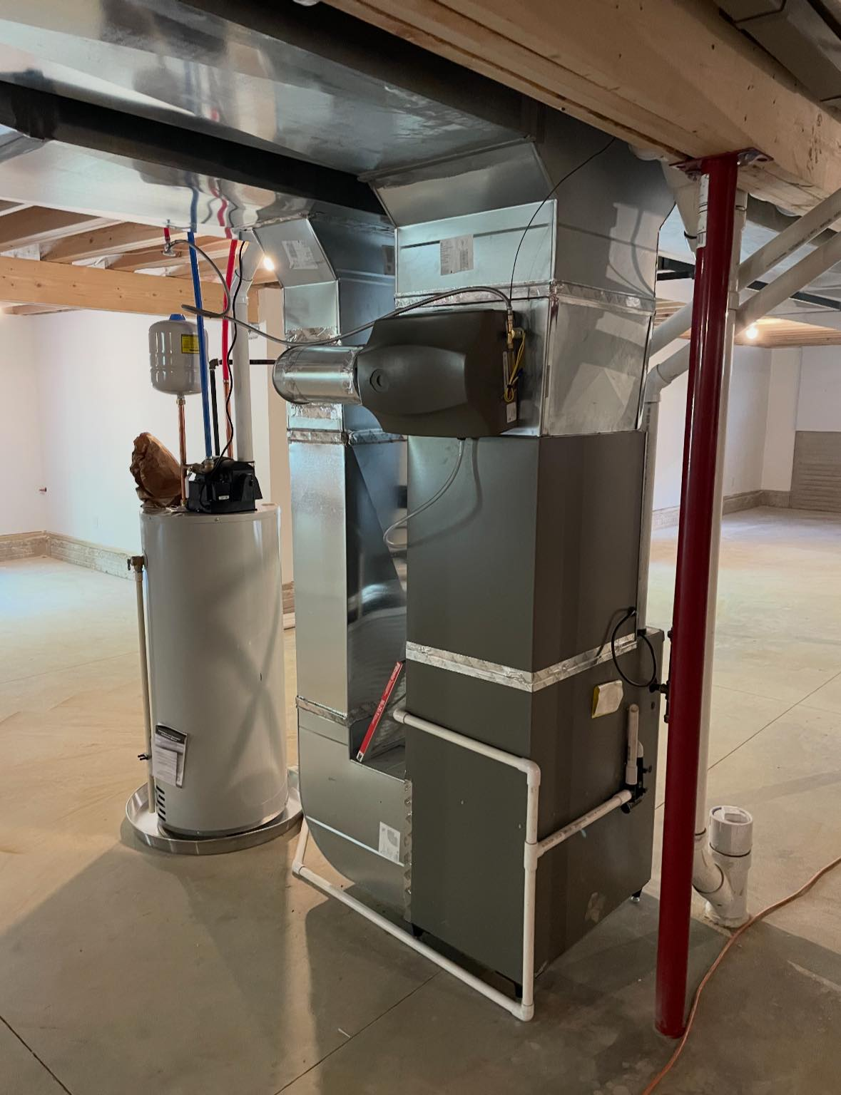 Basement HVAC furnace with ductwork and water heater beside red support post