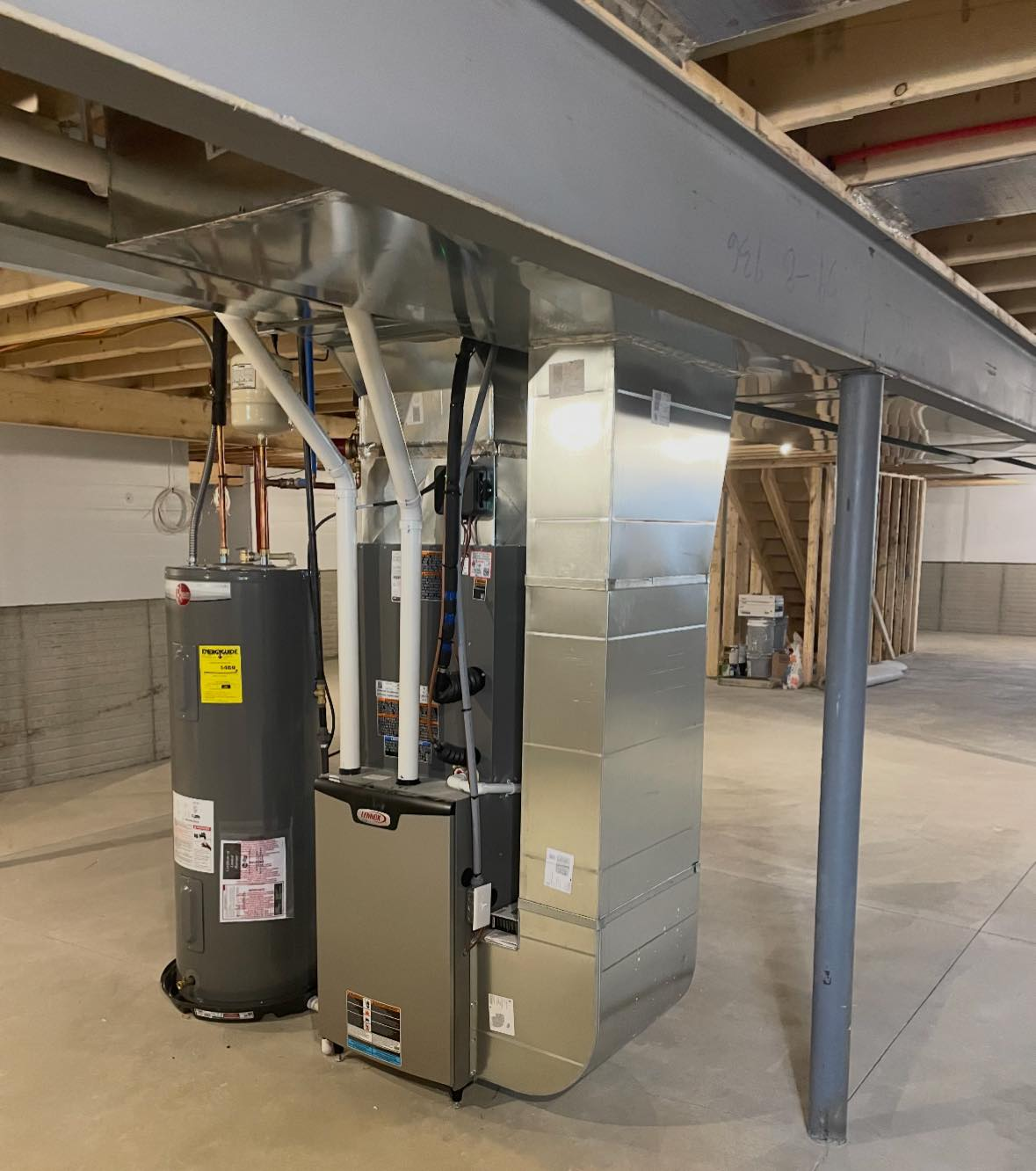 HVAC furnace and water heater in an unfinished basement under exposed ductwork