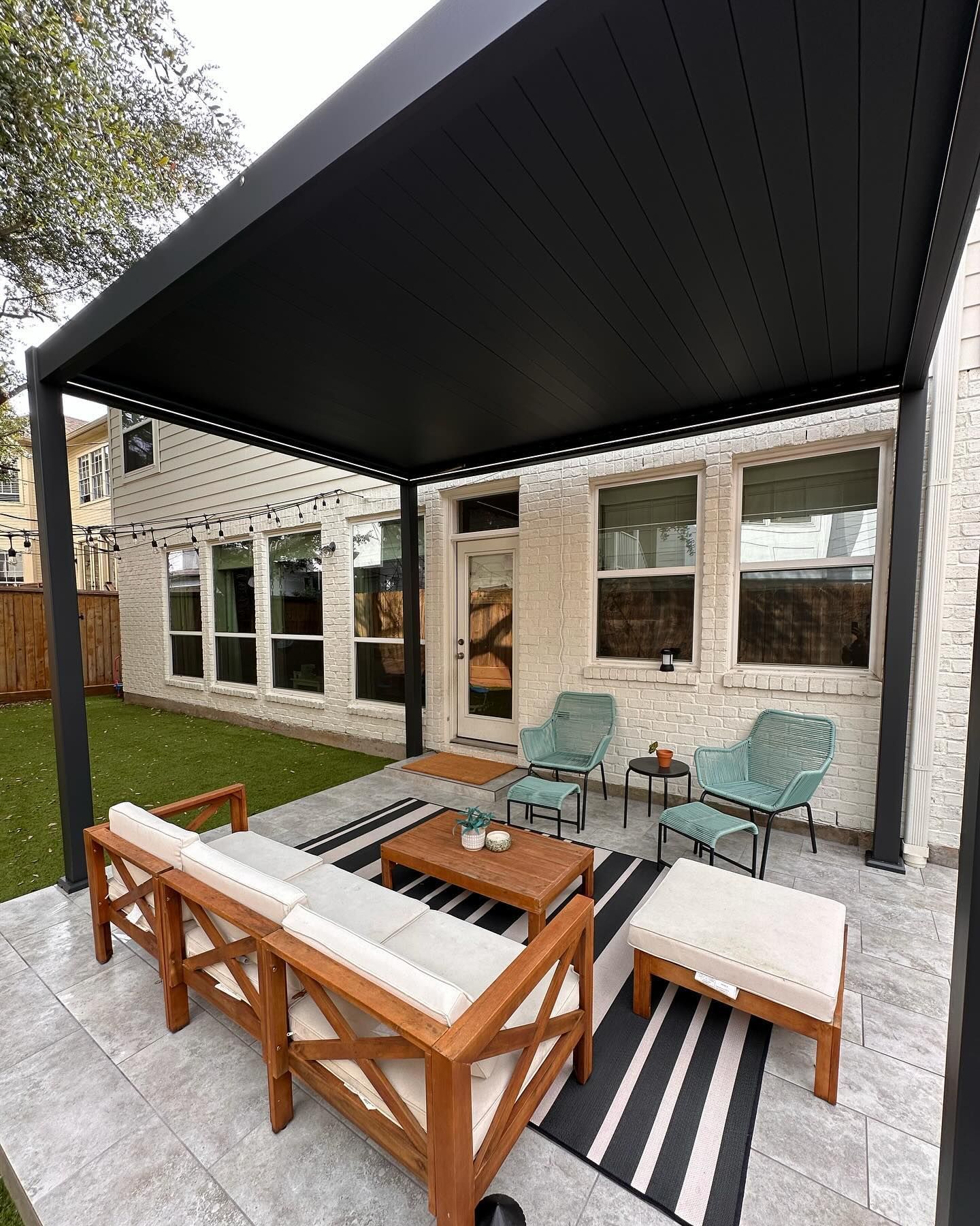 Black pergola over a patio with outdoor furniture