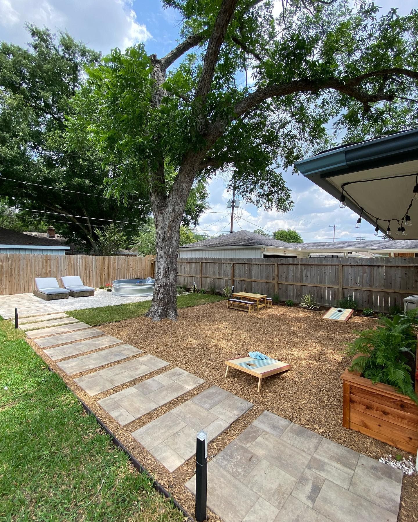 Backyard with stone path, lounge chairs, and games