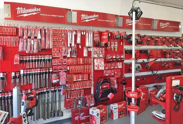 Milwaukee tool display wall with red-packaged drills, bits, and accessories in a store aisle