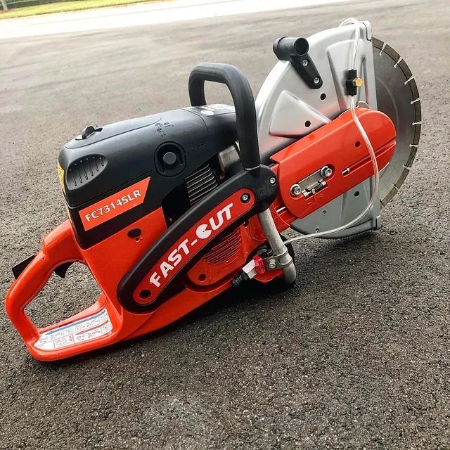 Orange and black FAST-CUT concrete saw with large blade on pavement outdoors