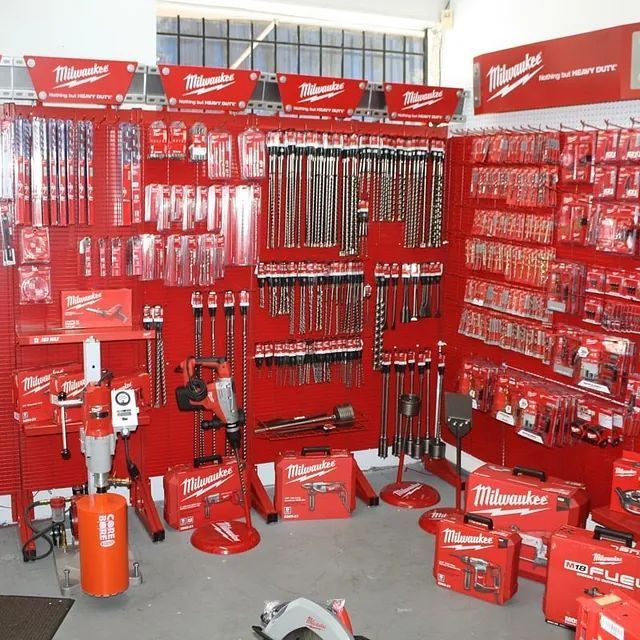 Red Milwaukee tool display with drills, saw blades, and red cases in a store aisle