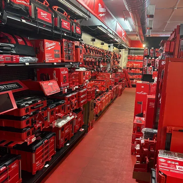 A store aisle stocked with red Milwaukee power tool cases and tools on both sides.