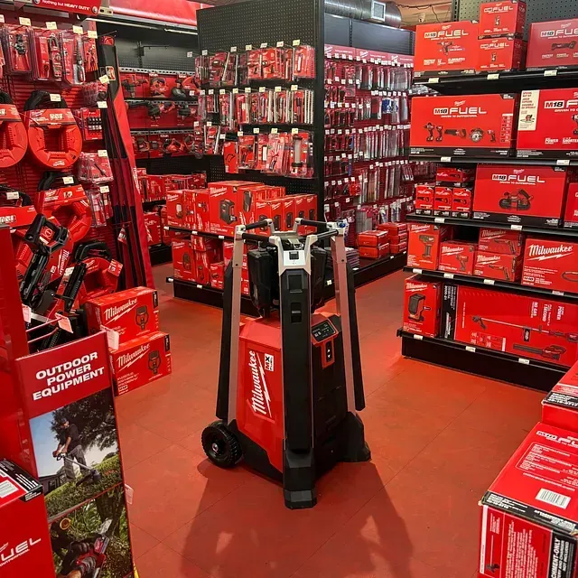 Red Milwaukee tool display in a hardware store aisle with red shelving and boxed products