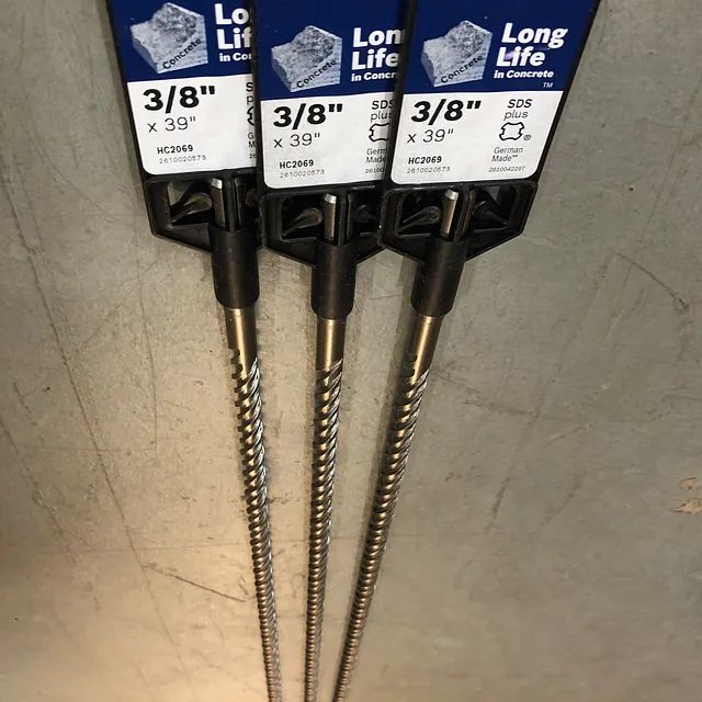 Three 3/8-inch silver auger screws in blue-and-white packaging on a gray surface