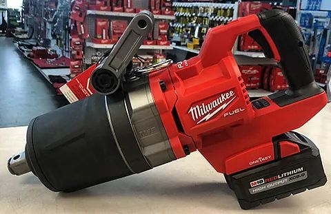 Red Milwaukee power tool with black attachment, resting on a counter in a tool store.