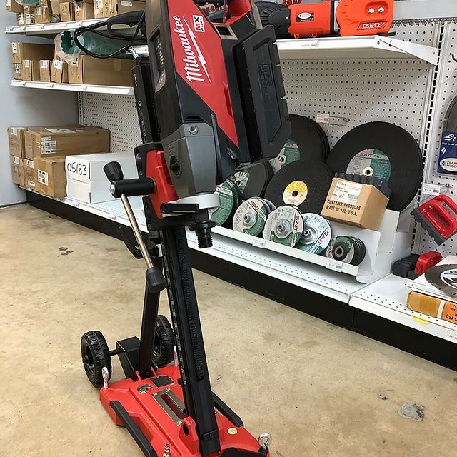 Red and black Milwaukee upright vacuum on a store shelf aisle with accessories displayed nearby