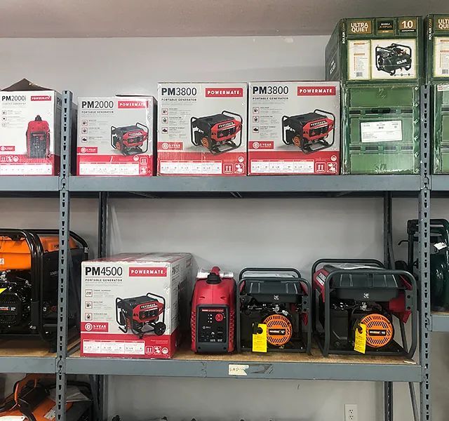 Shelves of boxed generators and fuel cans in a store or workshop, with red and black power equipment displayed.