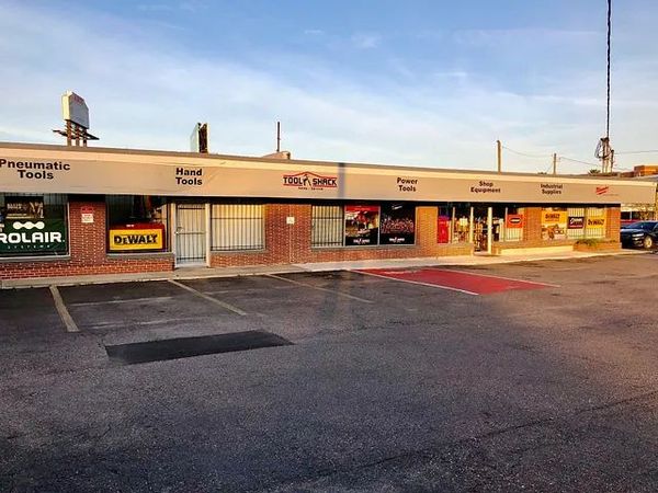 Strip mall storefronts at sunset with several business signs and an empty parking lot