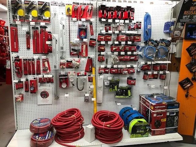 Hardware store display of red extension cords, tools, and electrical supplies on pegboard shelves