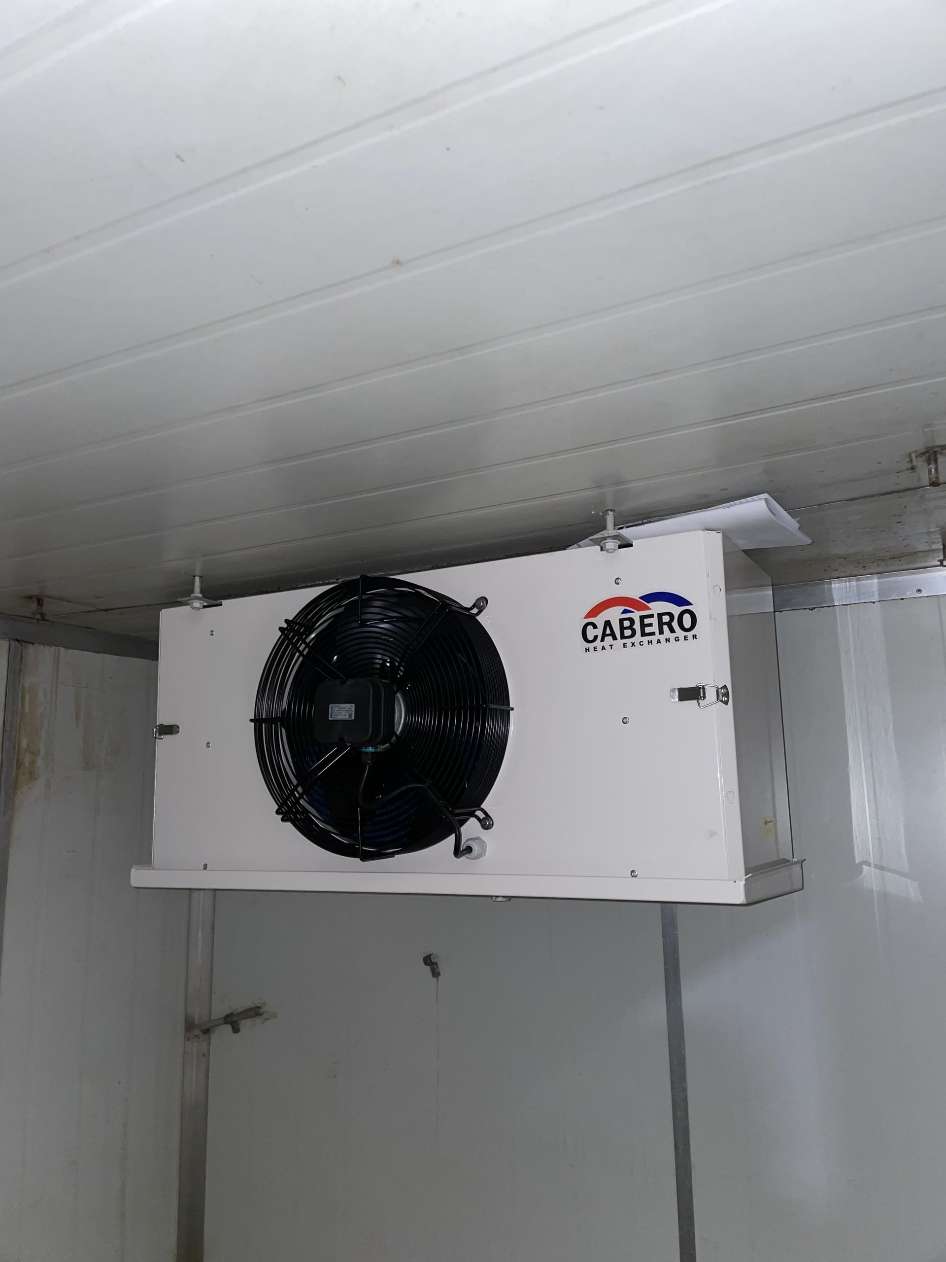 White wall-mounted cooling unit with a black fan in a white room— Deltech HVACR in Georgetown, NSW