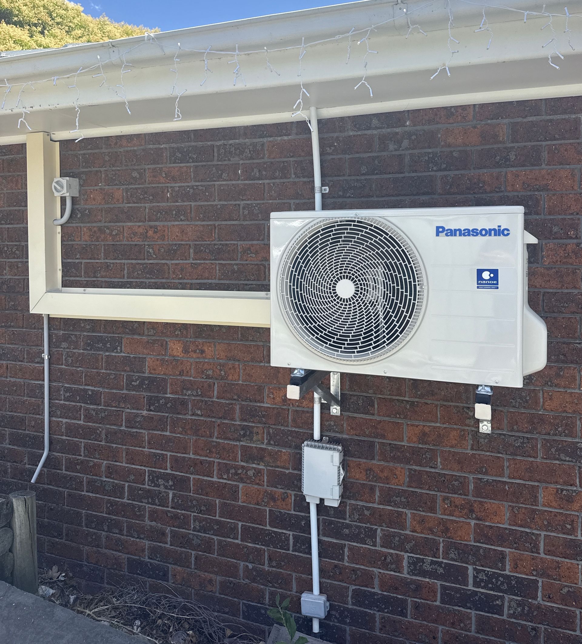 Outdoor wall-mounted HVAC unit on a brick building with heavy snow/ice on the fan grille and roof edge — Deltech HVACR in Georgetown, NSW