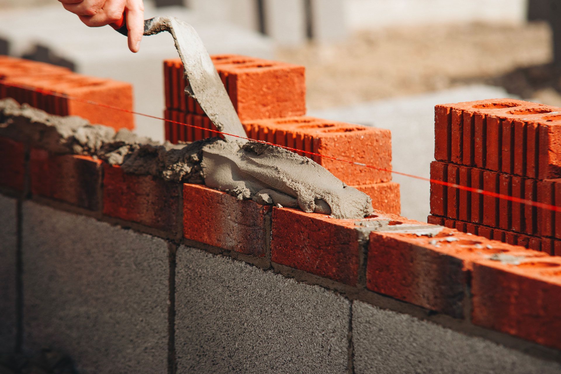Worker spreading mortar on a brick wall under construction